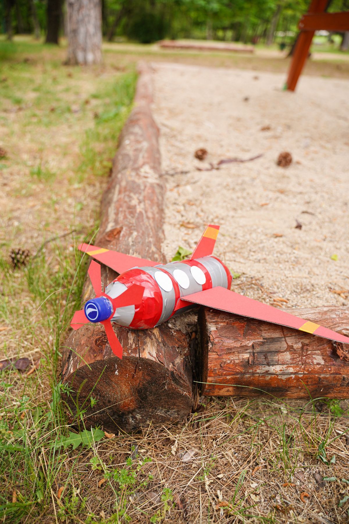 wood edging on playground with red and silver airplane on top