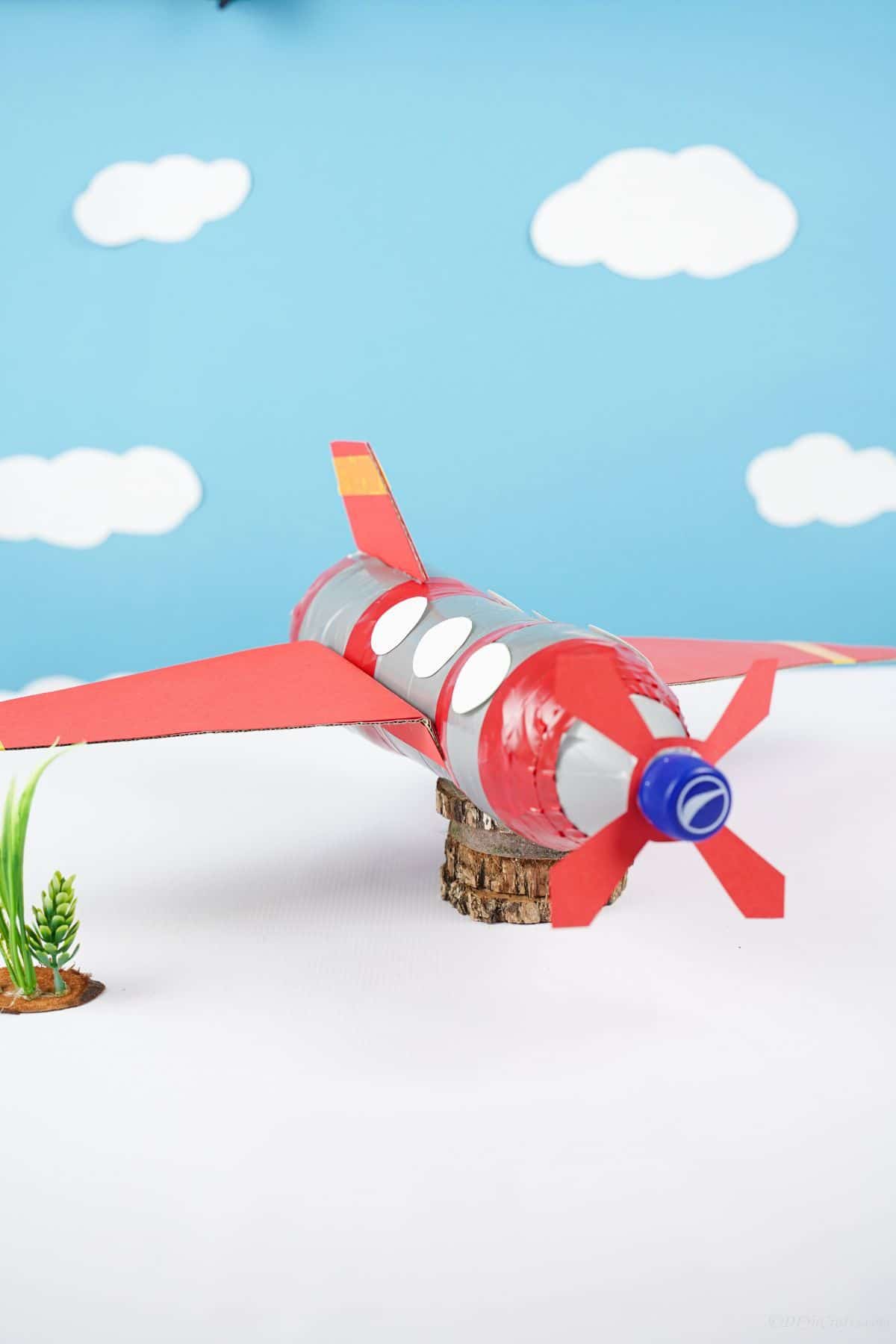 blue background with white clouds behind plastic bottle airplane toy