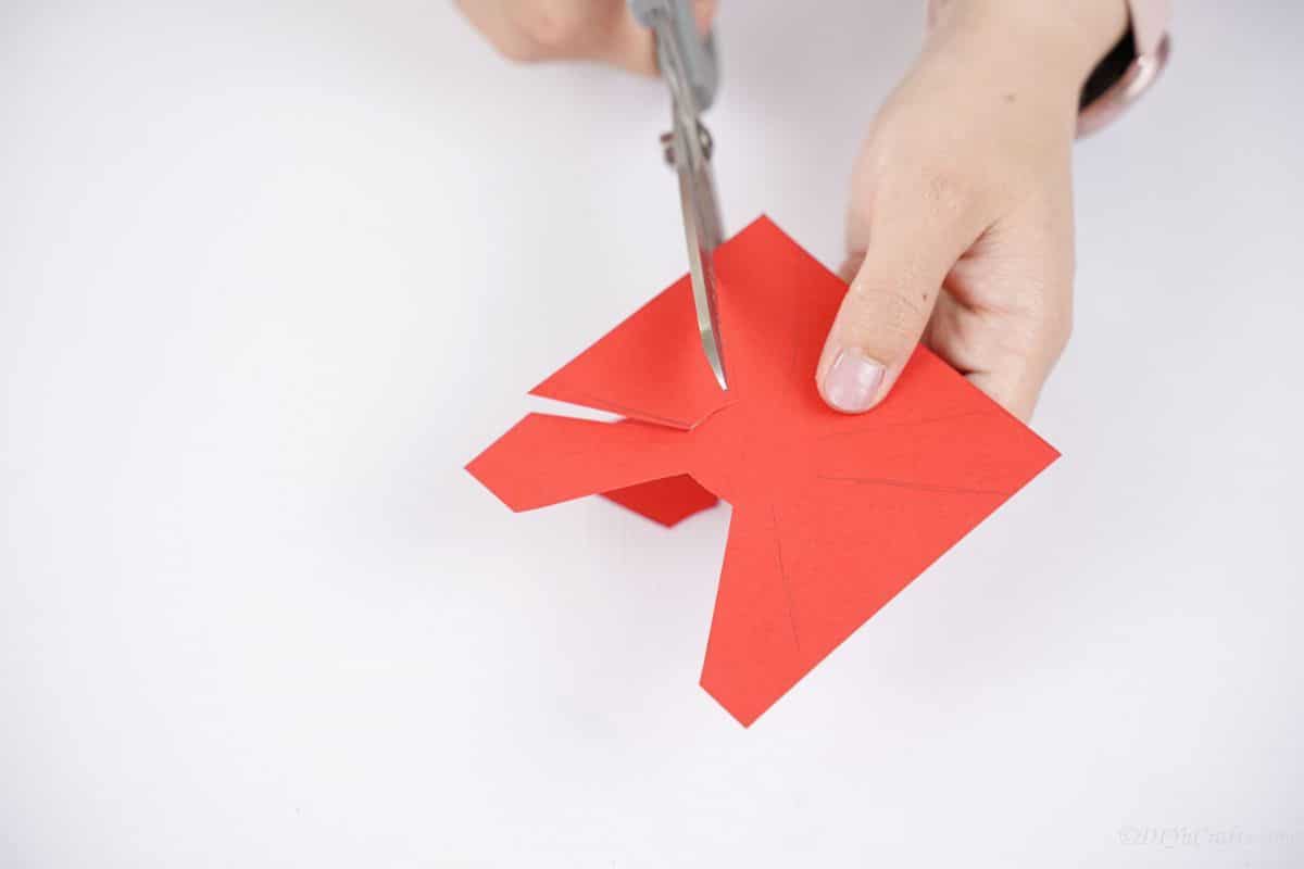 gray scissors being used to cut out red paper