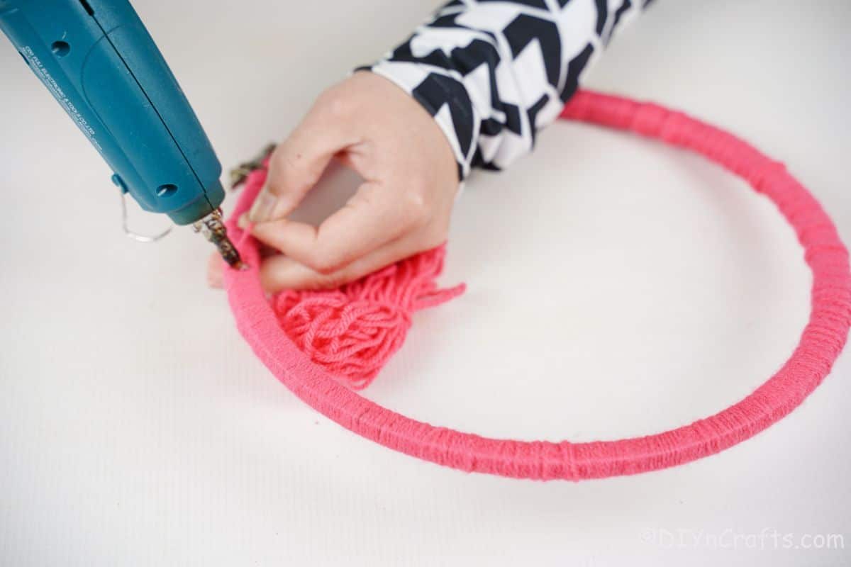 pink yarn wrapped around embroidery hoop being glued into place