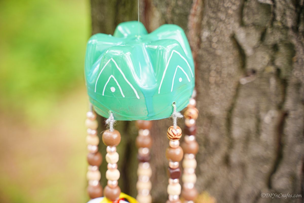 green and white top on wind chime in front of tree