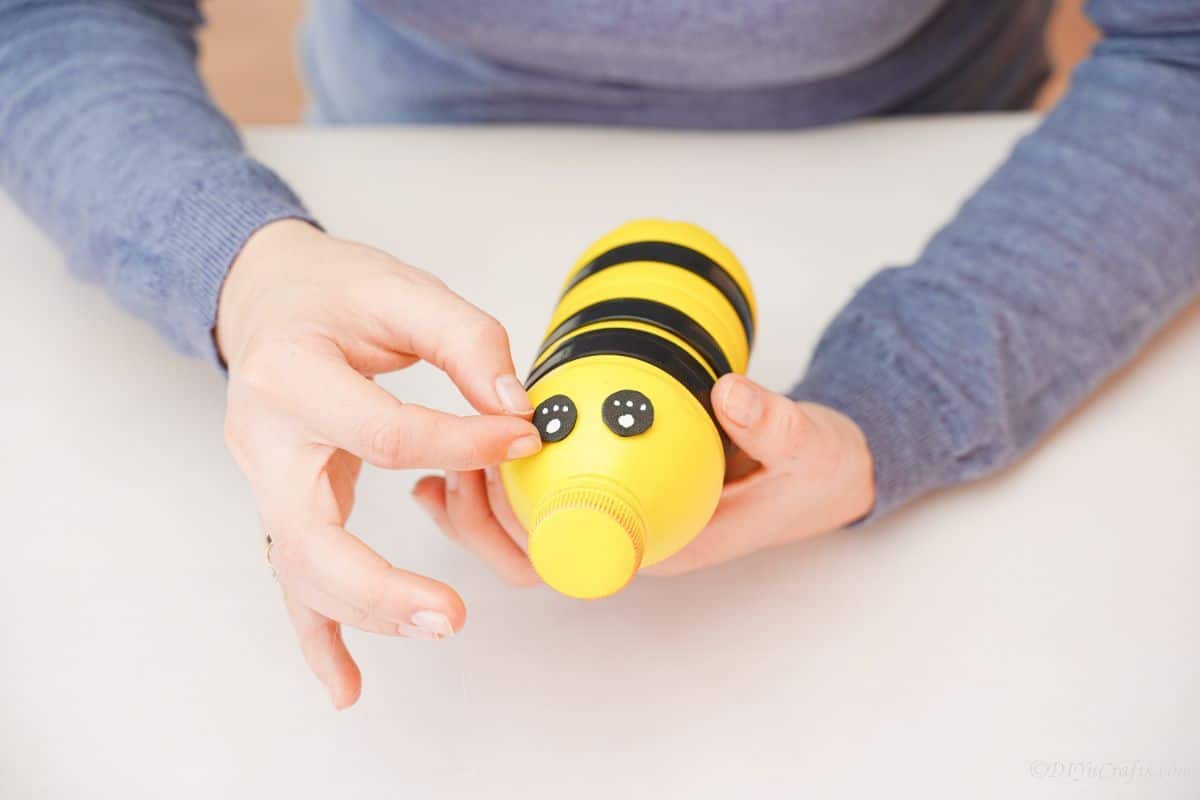 hand holding felt eye on top of bee bottle