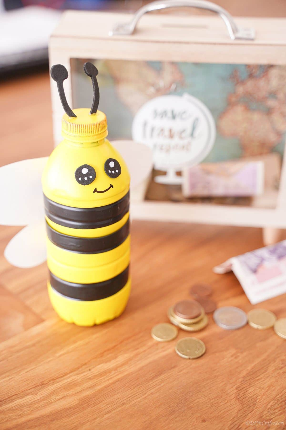 plastic bottle bumblebee bank on table next to ticket shadowbox