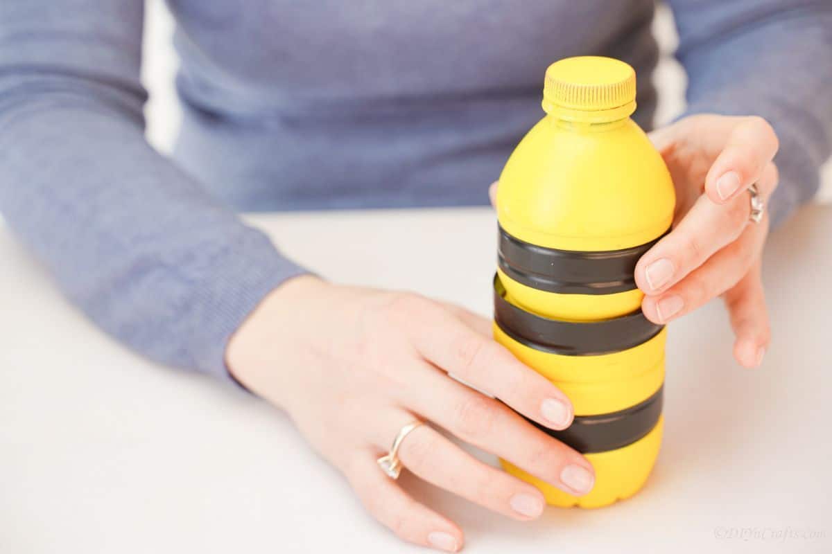 yellow and black striped bottle held in woman hands