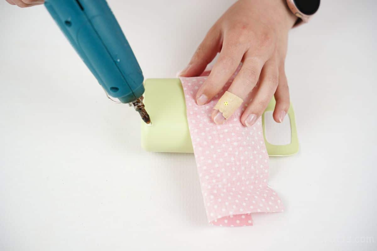 glue being put on green bottle with pink fabric