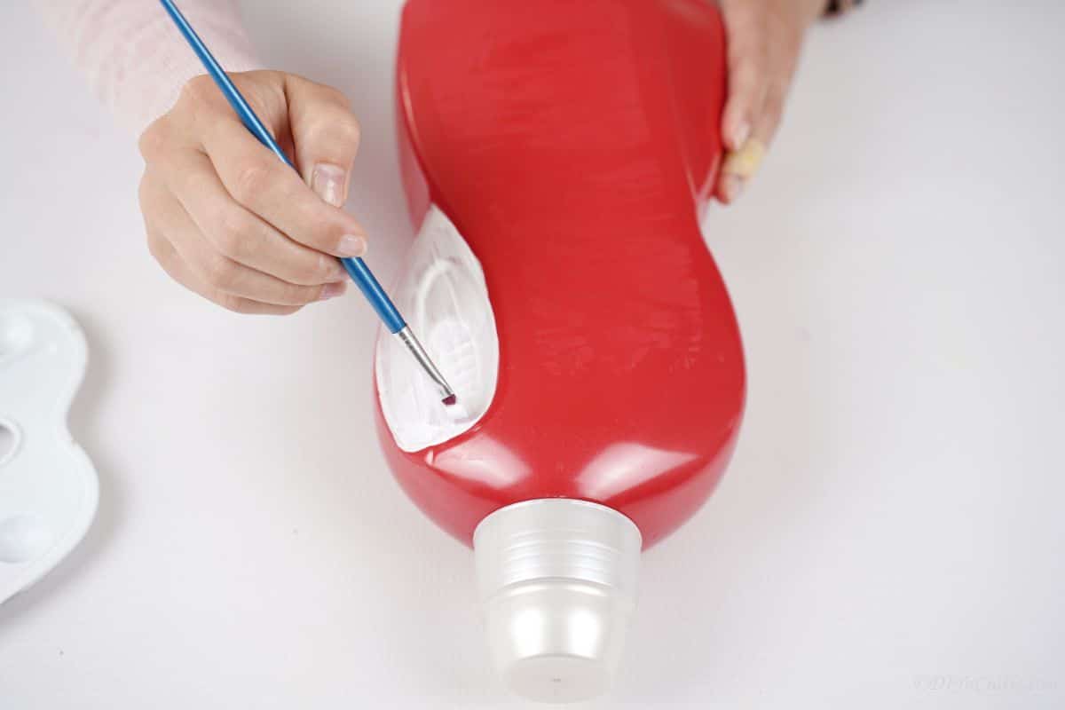 hand painting white on edges of red bottle