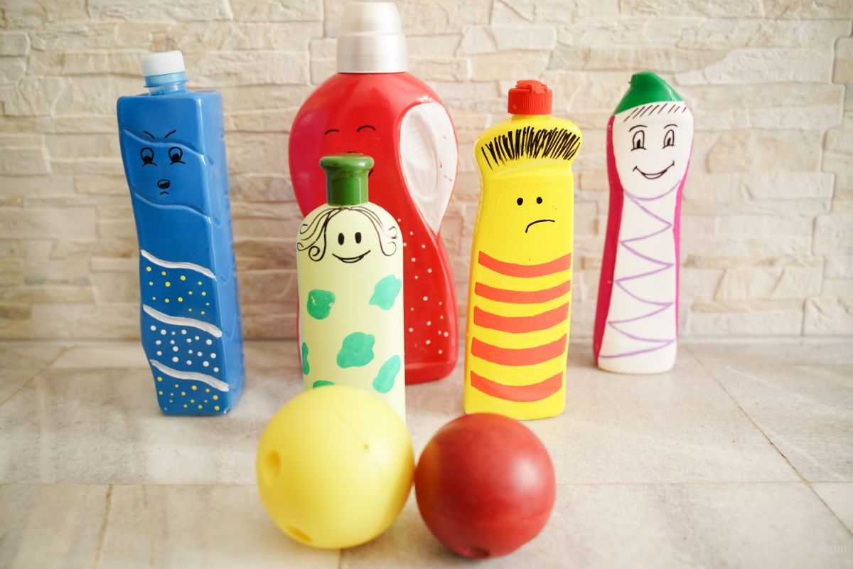 colorful painted bottles turned into character puppets on table with brick background
