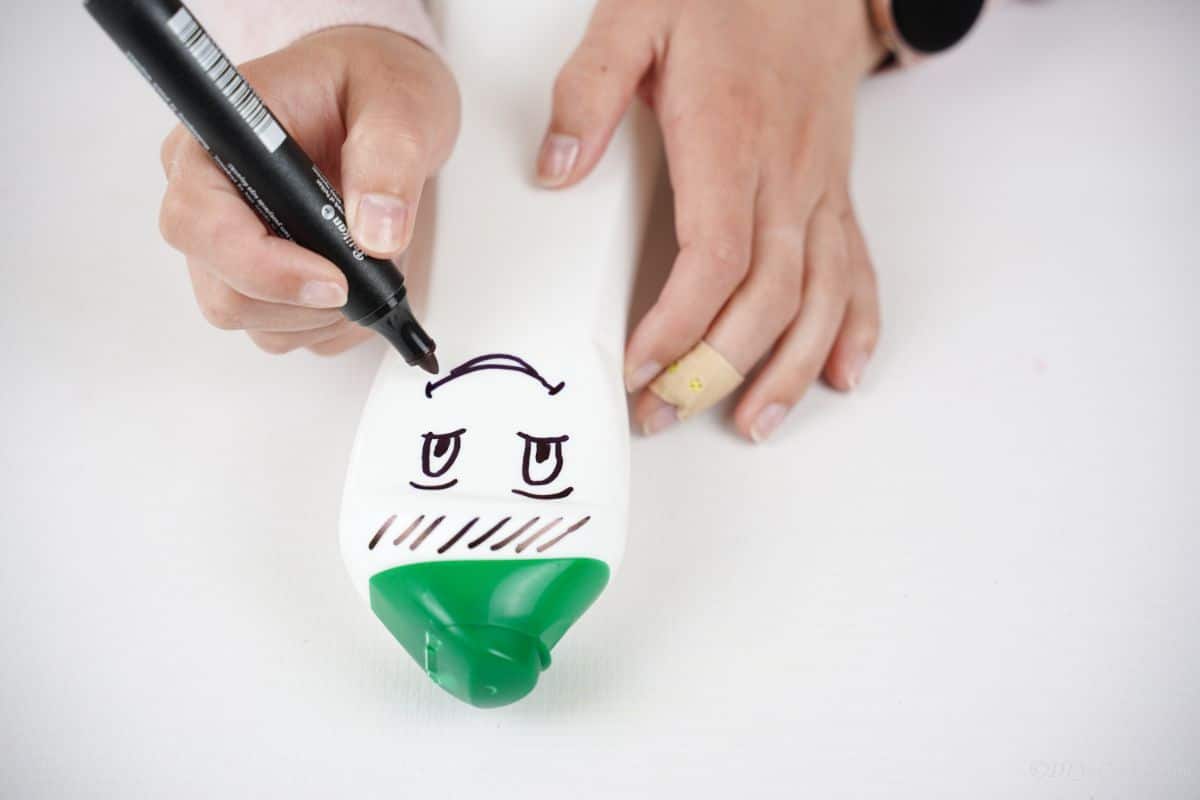 smile being drawn on front of white bottle with green top