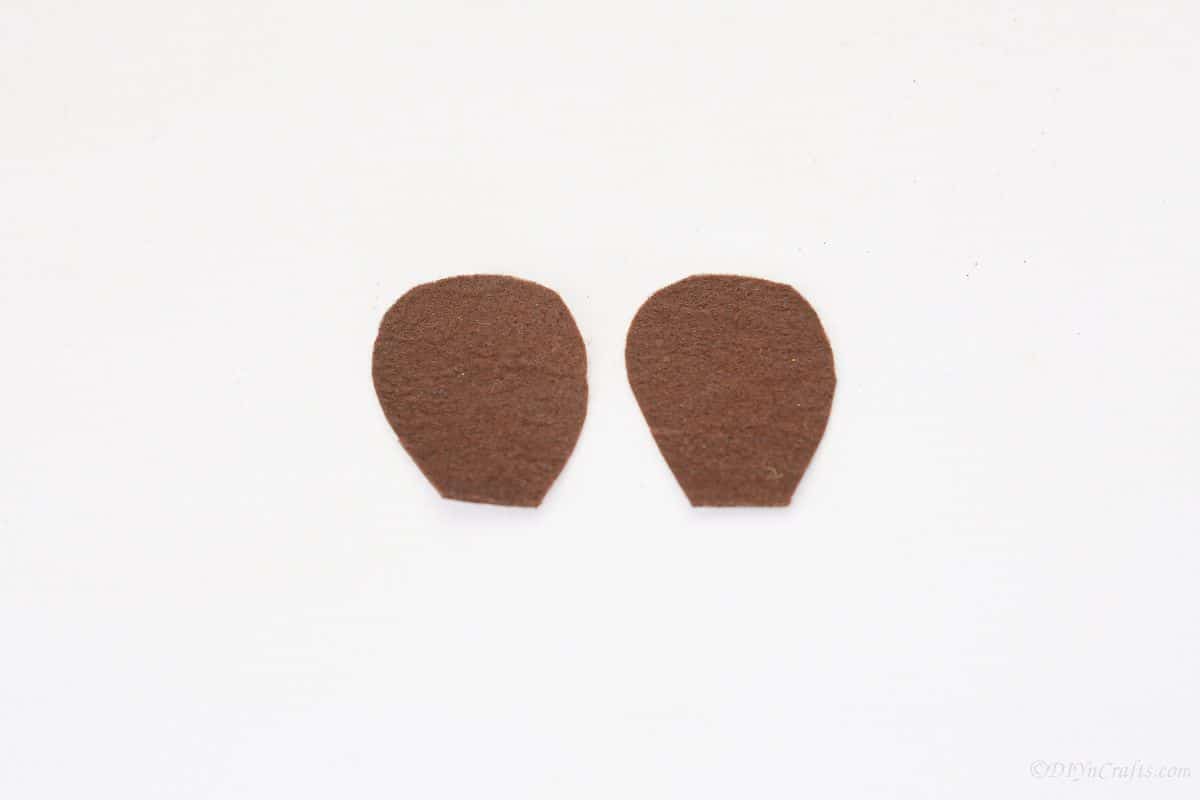 two oval brown felt ear pieces on white table
