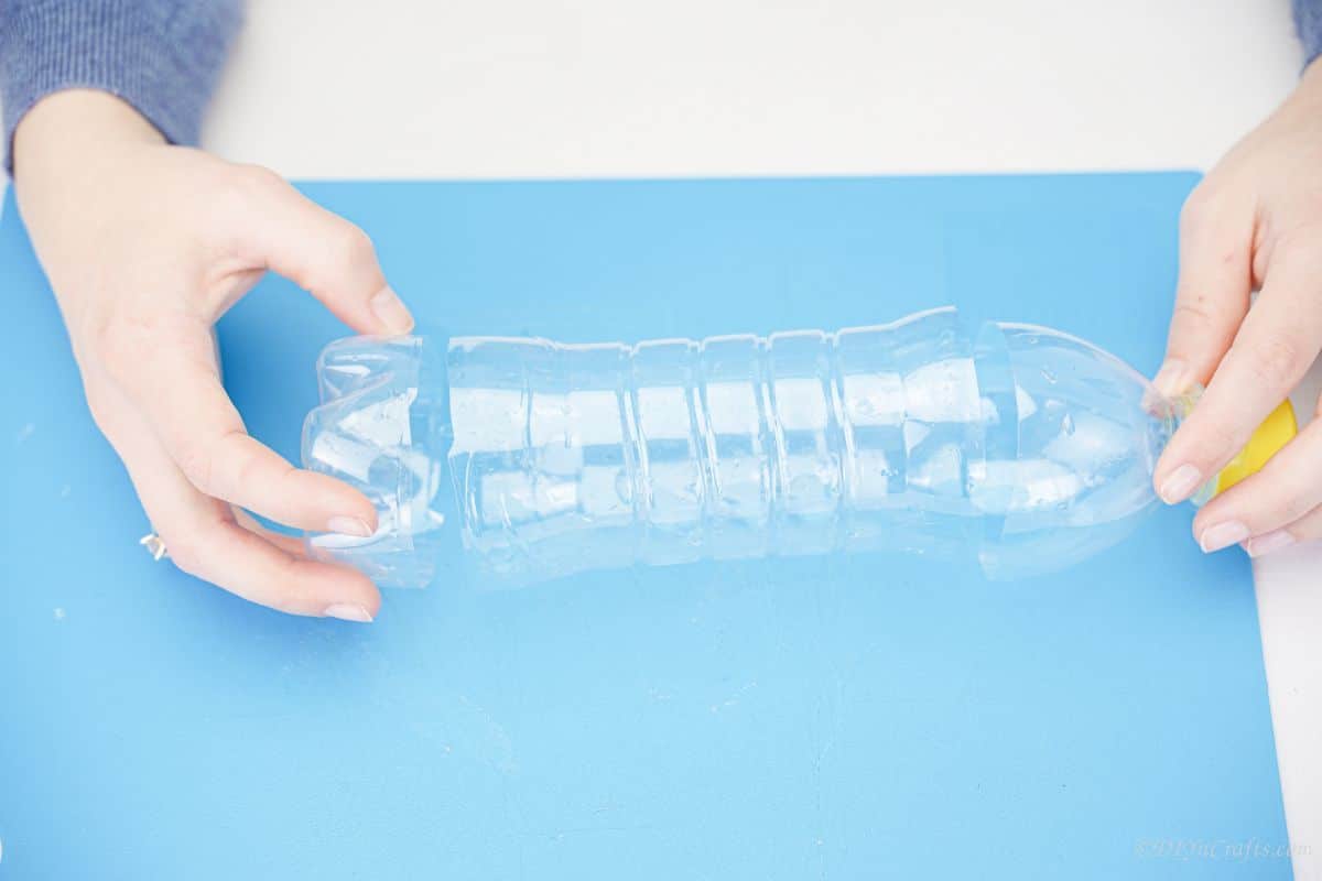 hand holding bottom of plastic bottle on blue mat