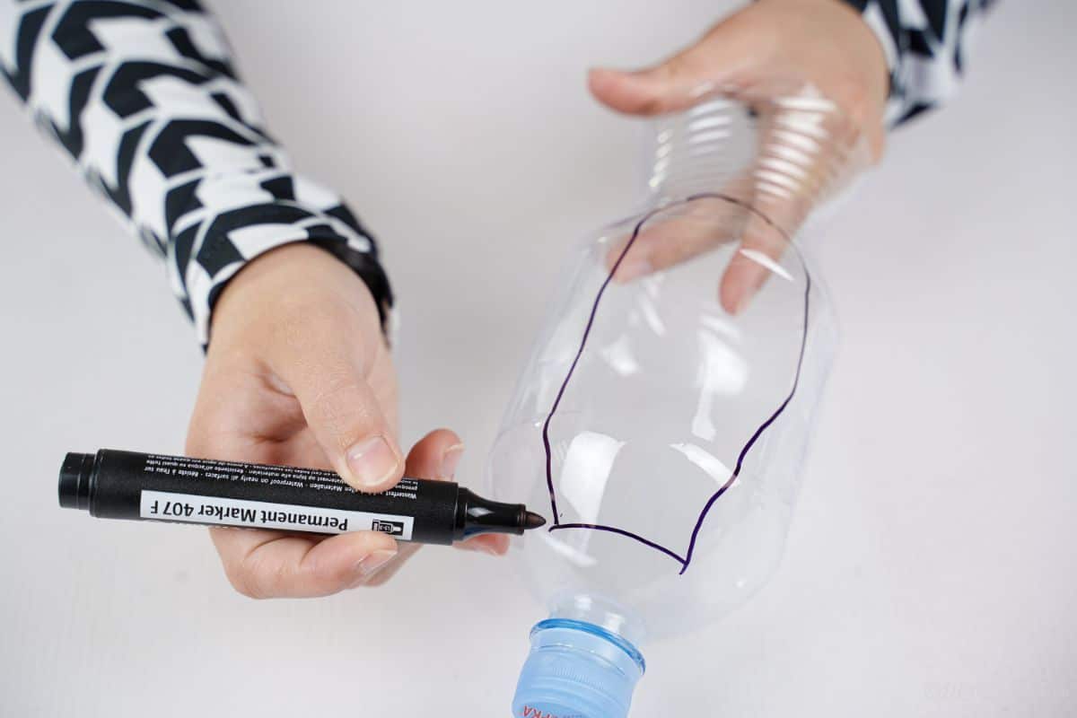 black marker cutting ear shape on plastic bottle