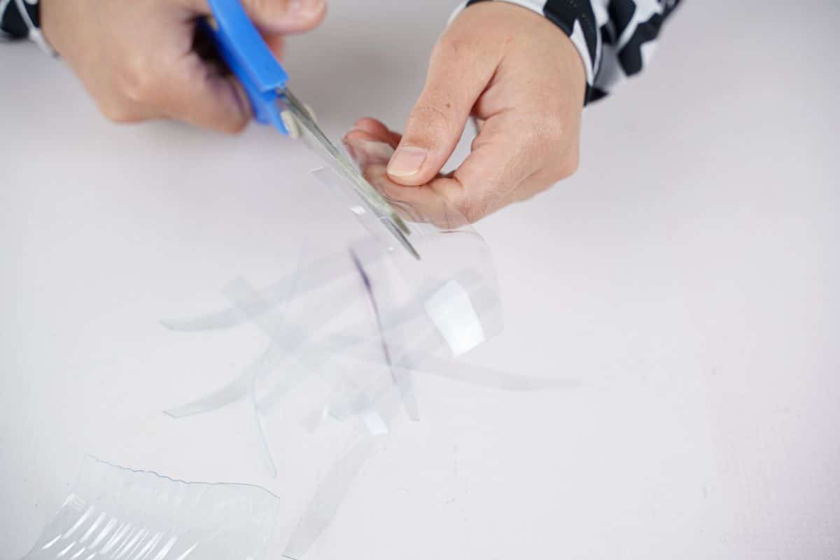 hand cutting strips of plastic bottle
