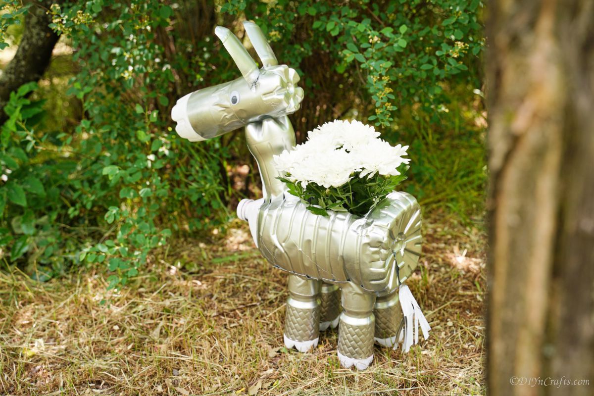 donkey painted silver with white horses inside on lawn by shrubs