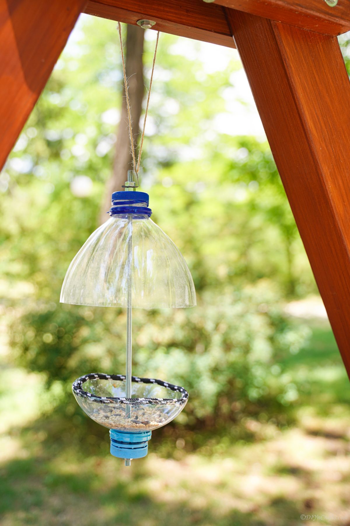 bird feeder hanging between wood beams on swings