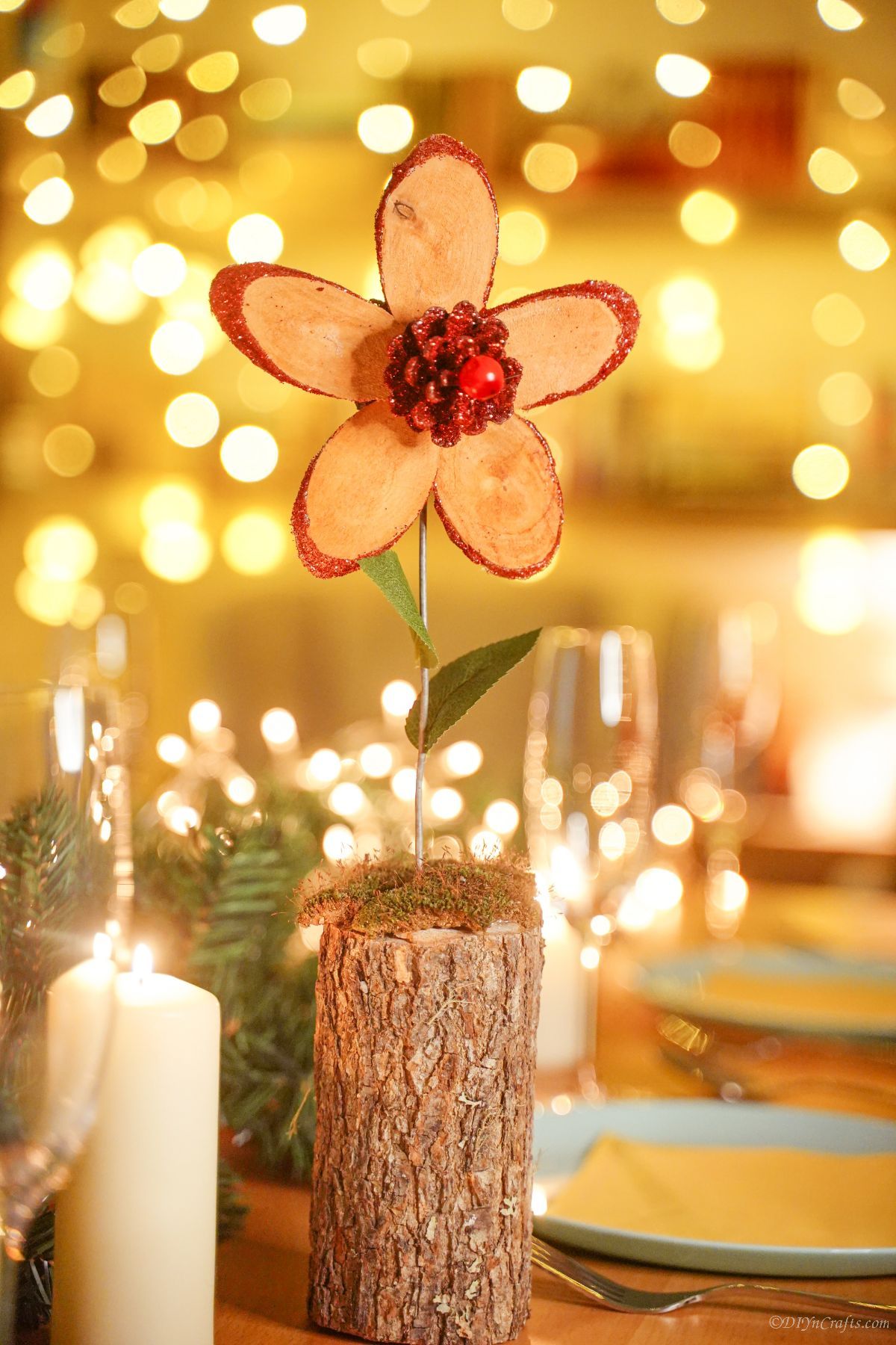 wood slice flower with red pinecone on front on table with place settings