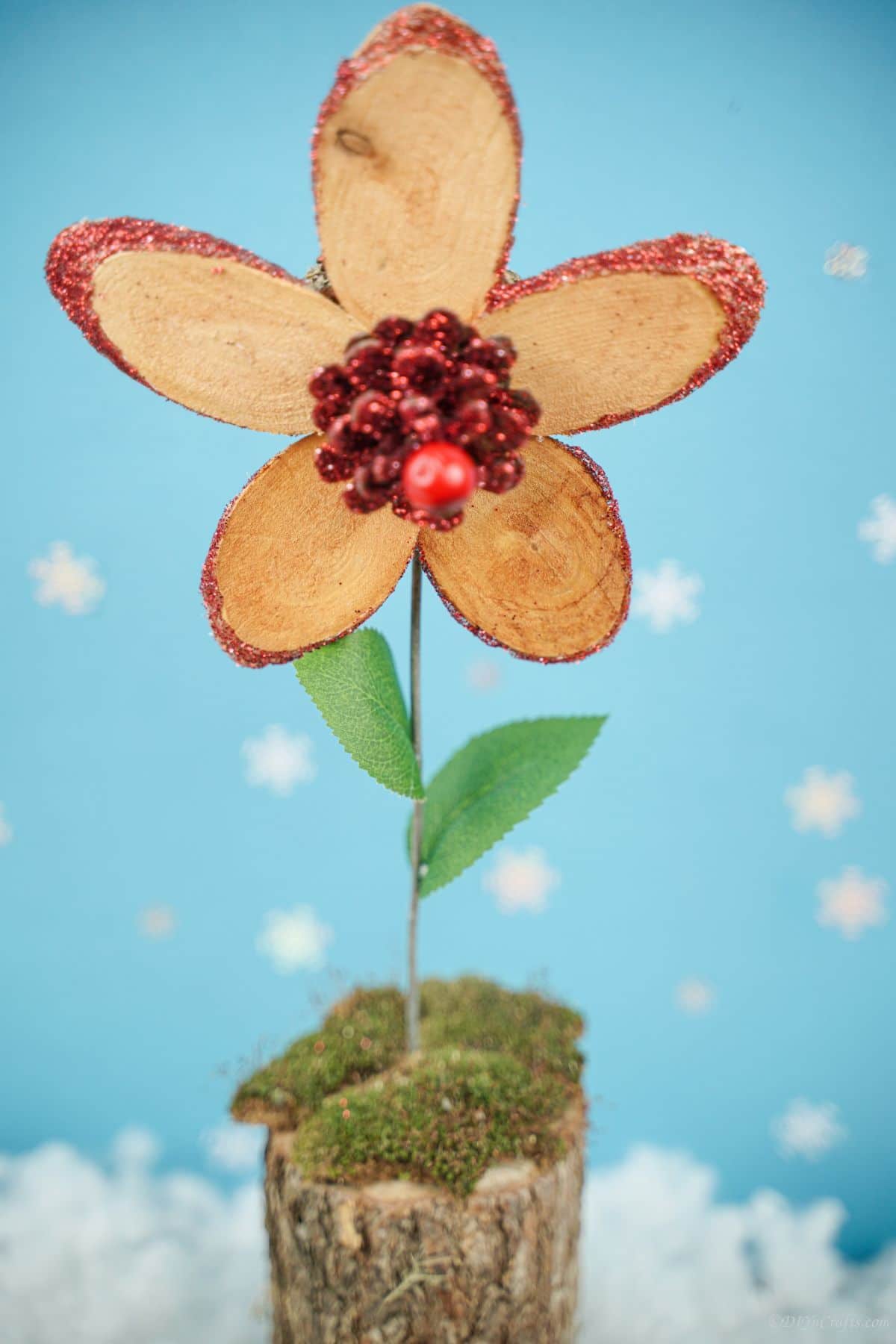 red glitter on wood slice flower sitting on table with blue background