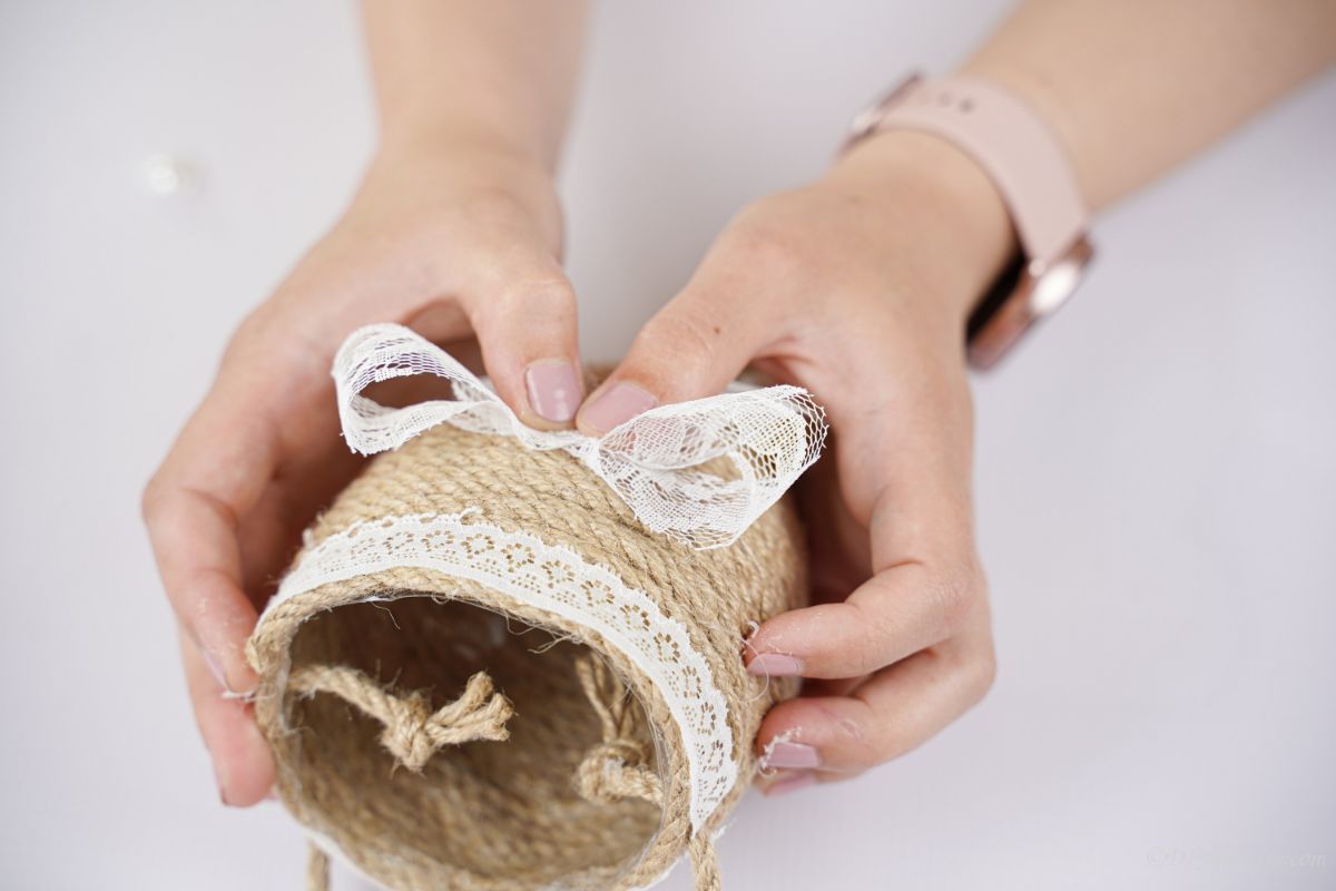 hands holding a lace bow in front of the planter