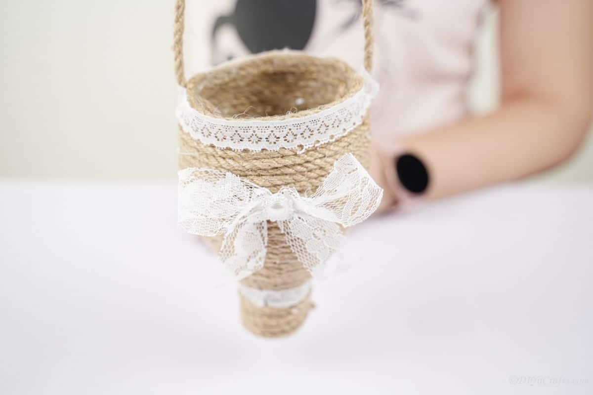 twine and lace planter being held above white table