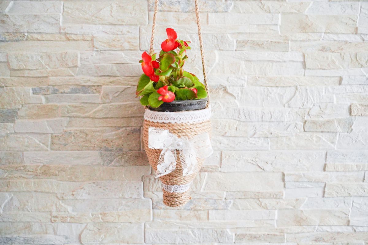red flowers in twine planter hanging on brick wall