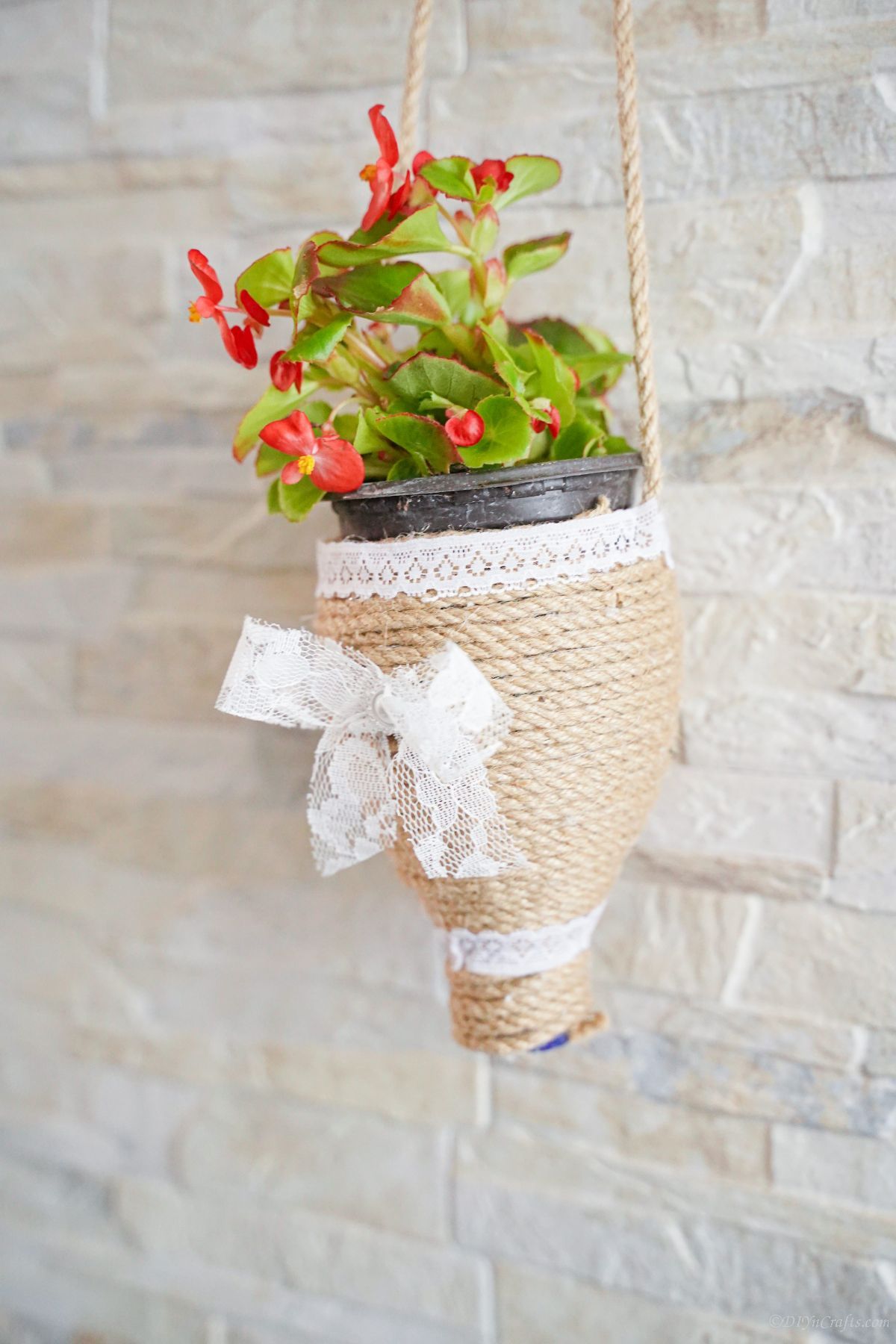 cream brick wall with twine planter holding red flowers