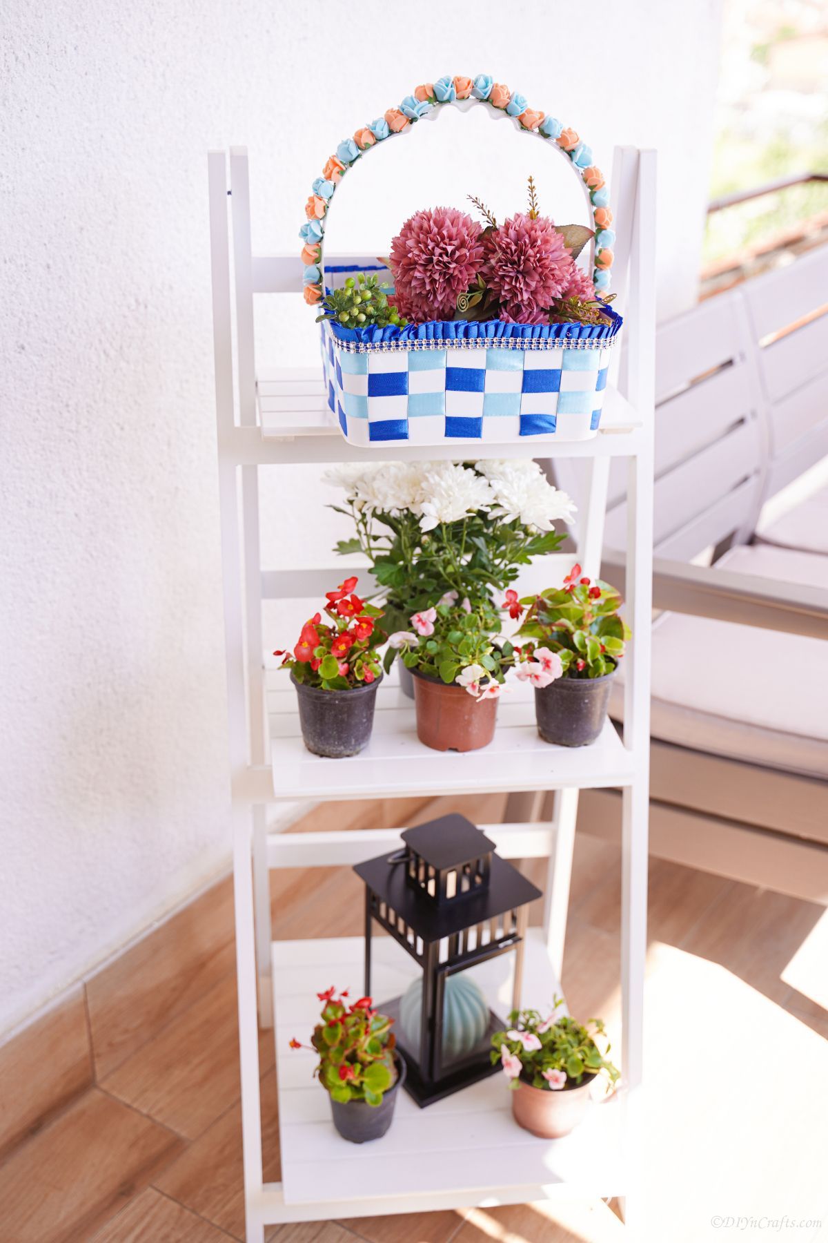 white ladder shelf holding planters and basket of flowers