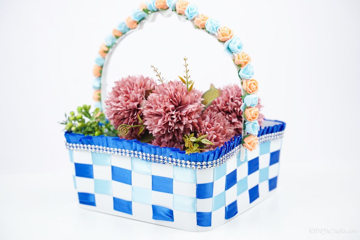 plastic basket with blue ribbon on white surface