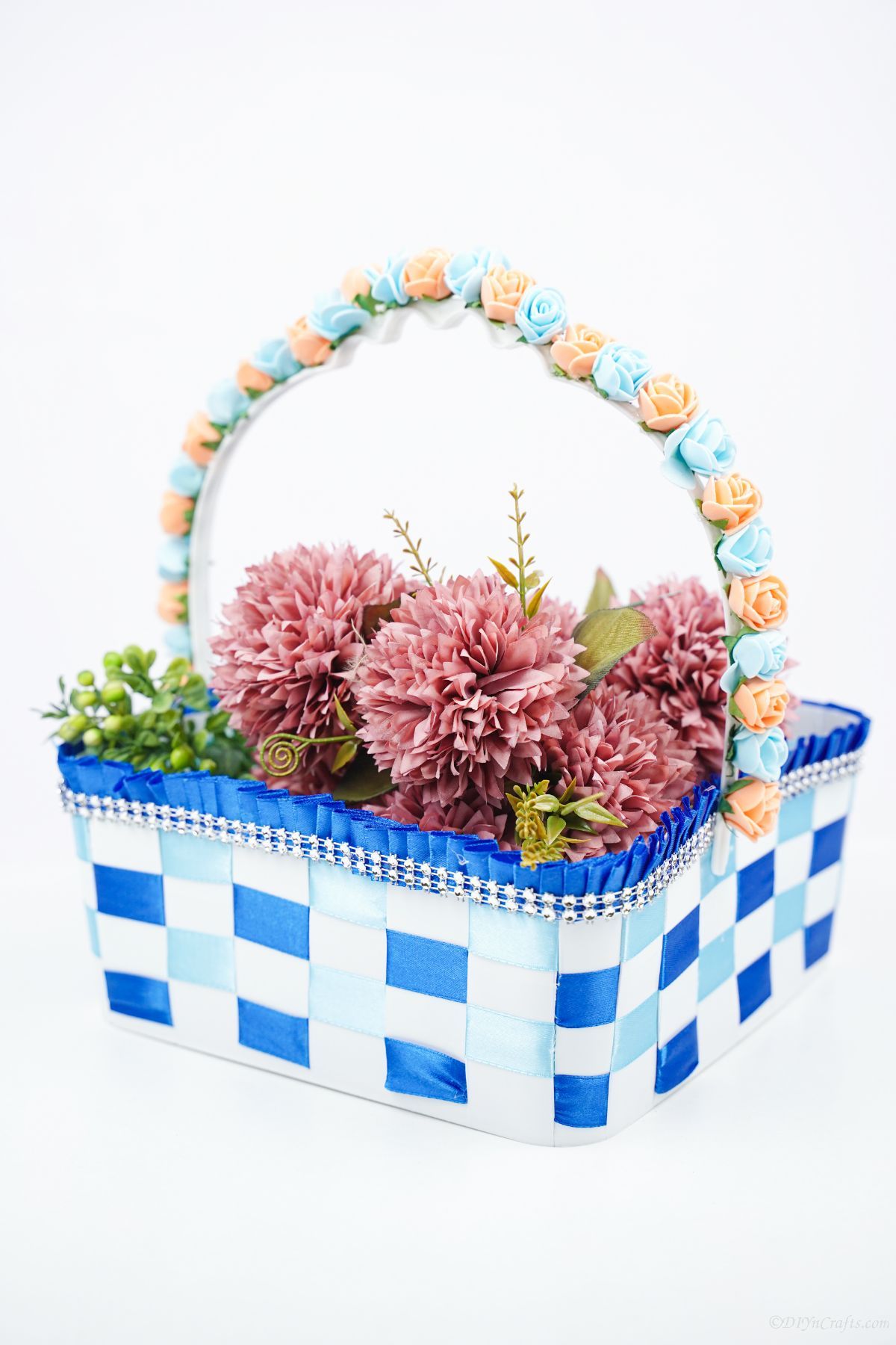 blue ribbon basket filled with pink flowers on white counter