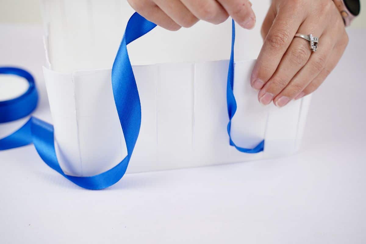 hand gluing ribbon to inside of plastic pail