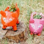 pink and red bottle pig planters on stump