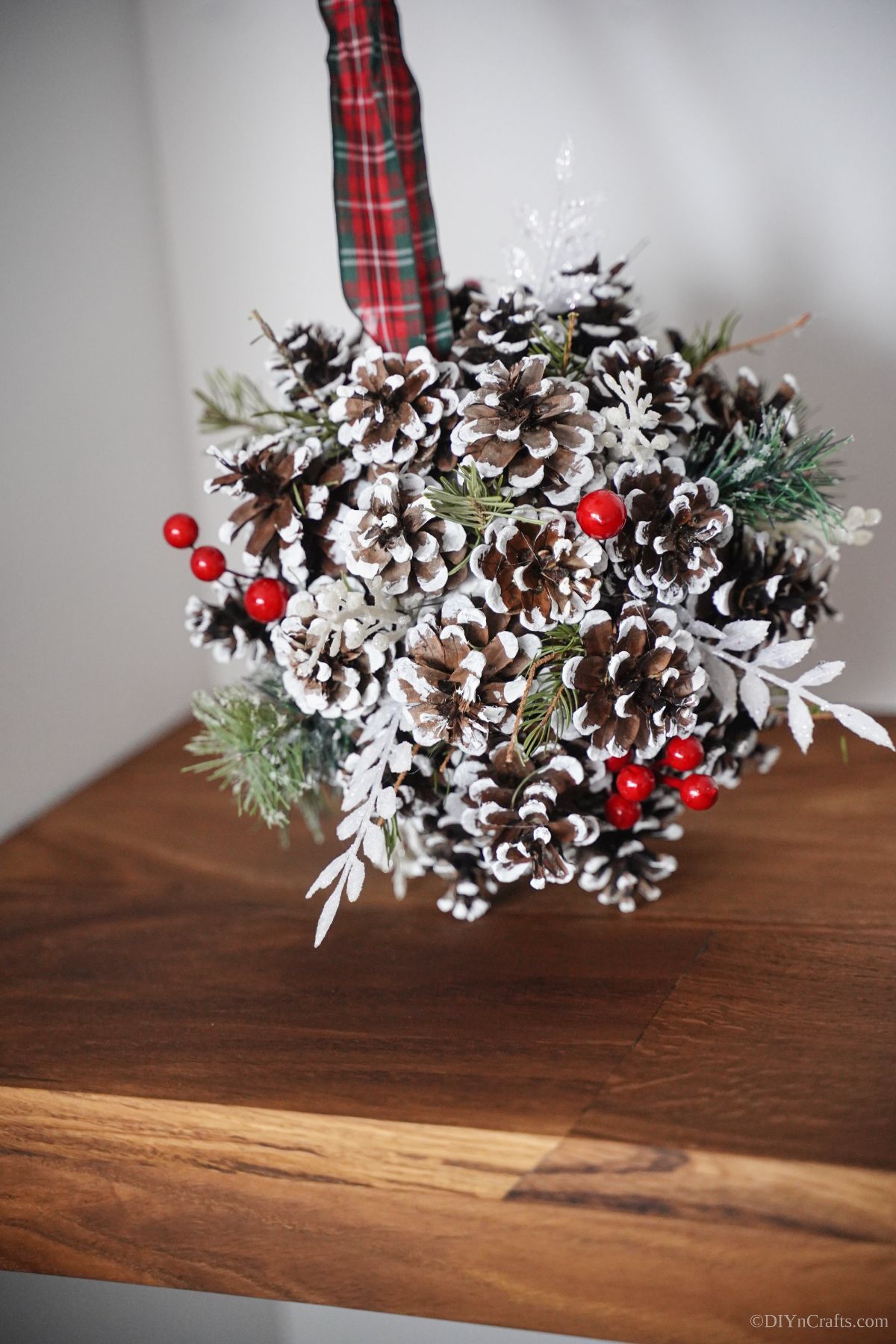 Christmas pinecone ball hanging against white wall