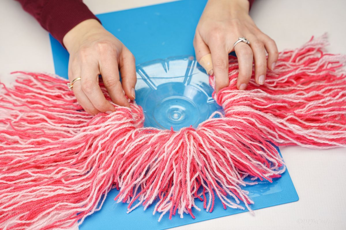 pink yarn plastic lid on blue mat