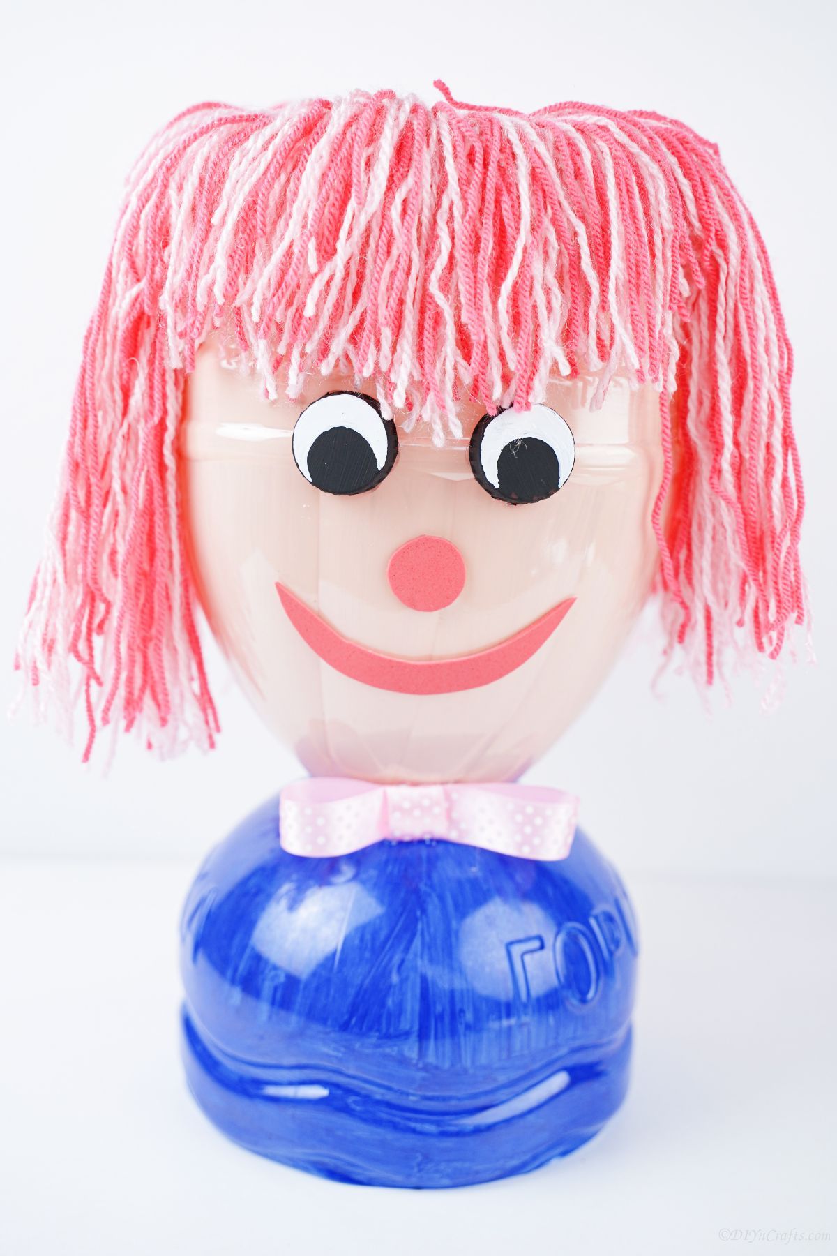 pink and blue plastic bottle doll on white table