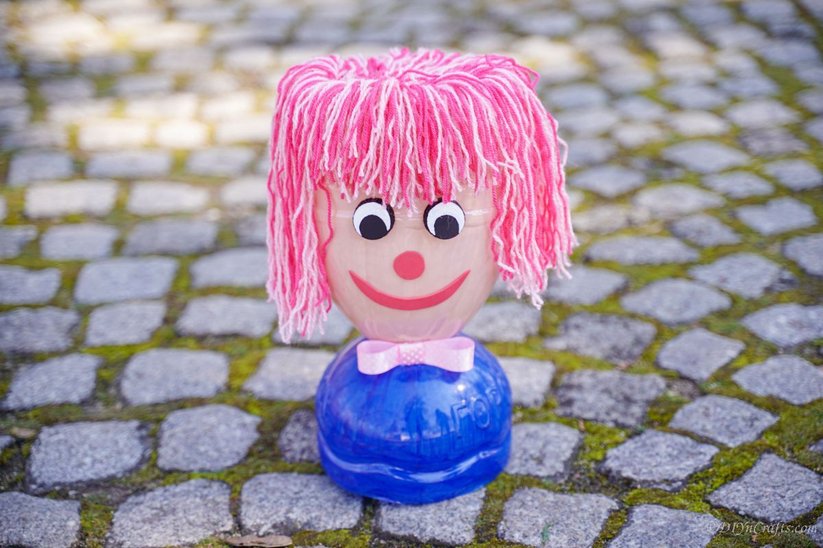 painted plastic bottle doll head on cobblestones