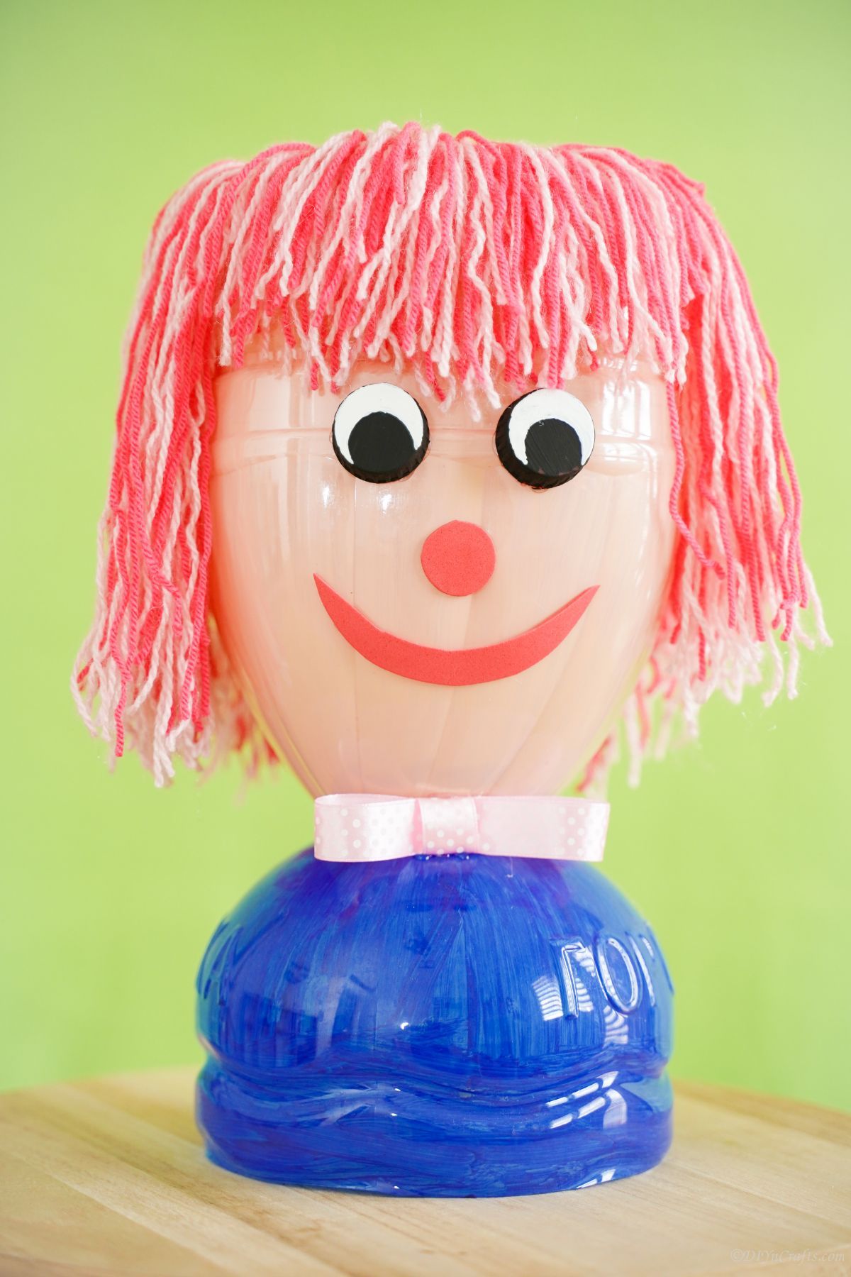 plastic bottle doll head with blue shirt on wood table 