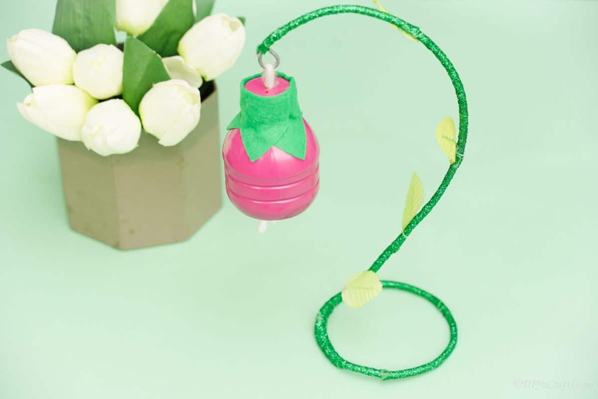 hanging plastic bottle flower on green table by potted tulips