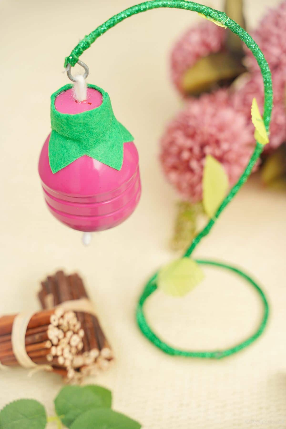 plastic bottle pink flower on green stem by cinnamon sticks