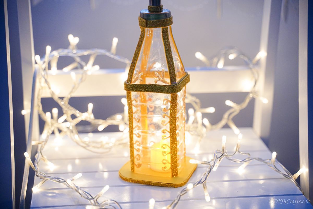 tealight candle lantern sa lamesa nga adunay mga christmas lights sa palibot niini