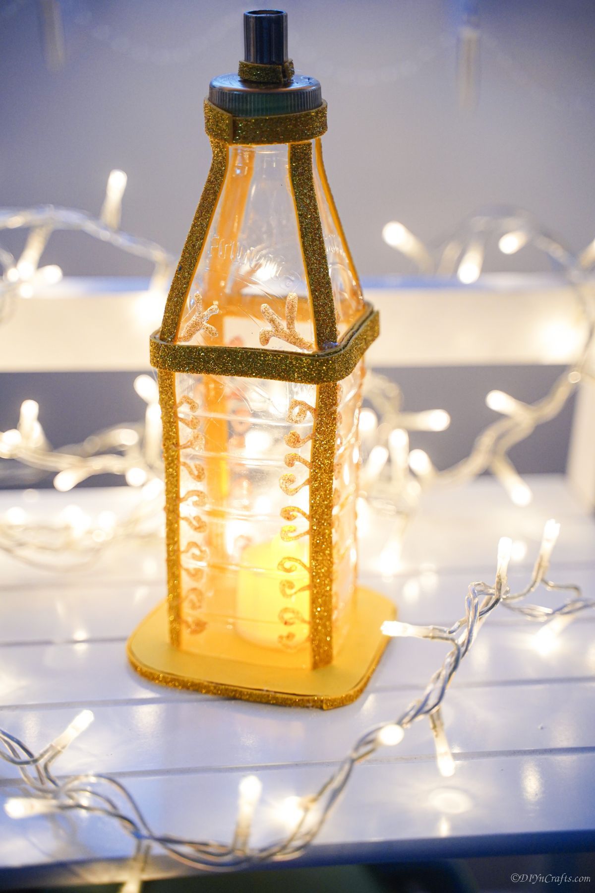 fake gold lantern on white table with christmas lights
