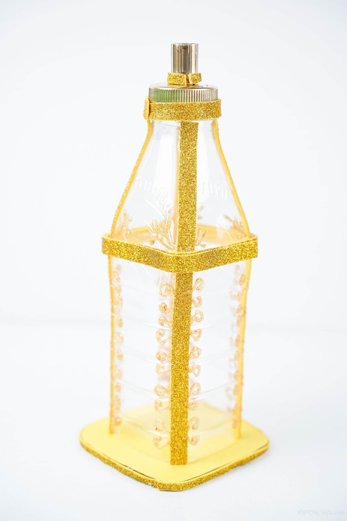 plastic bottle lantern with gold paint on white table