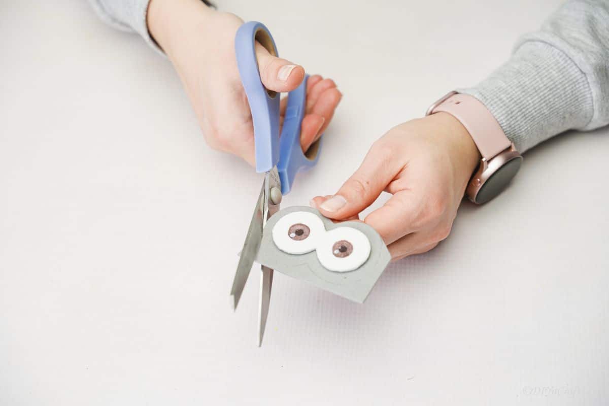 blue scissors cutting gray foam paper