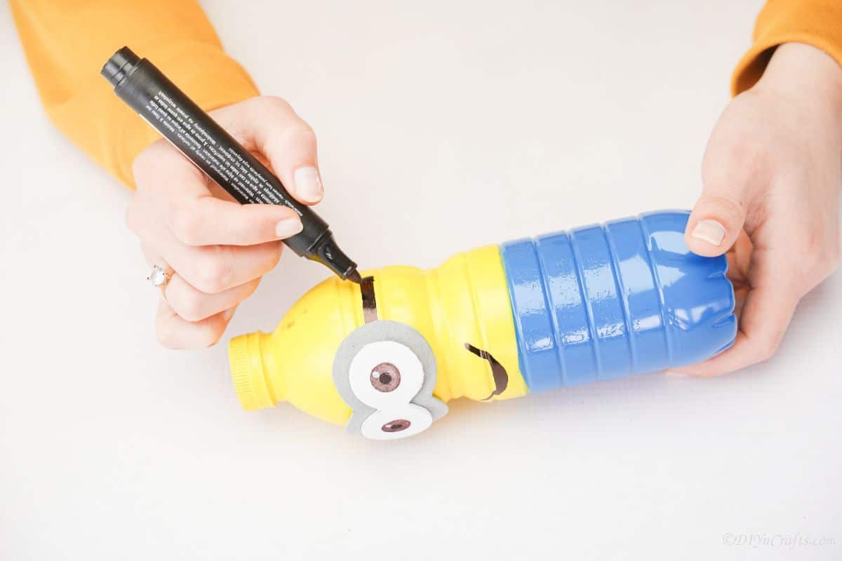 sharpie drawing goggle ear pieces on minion bottle