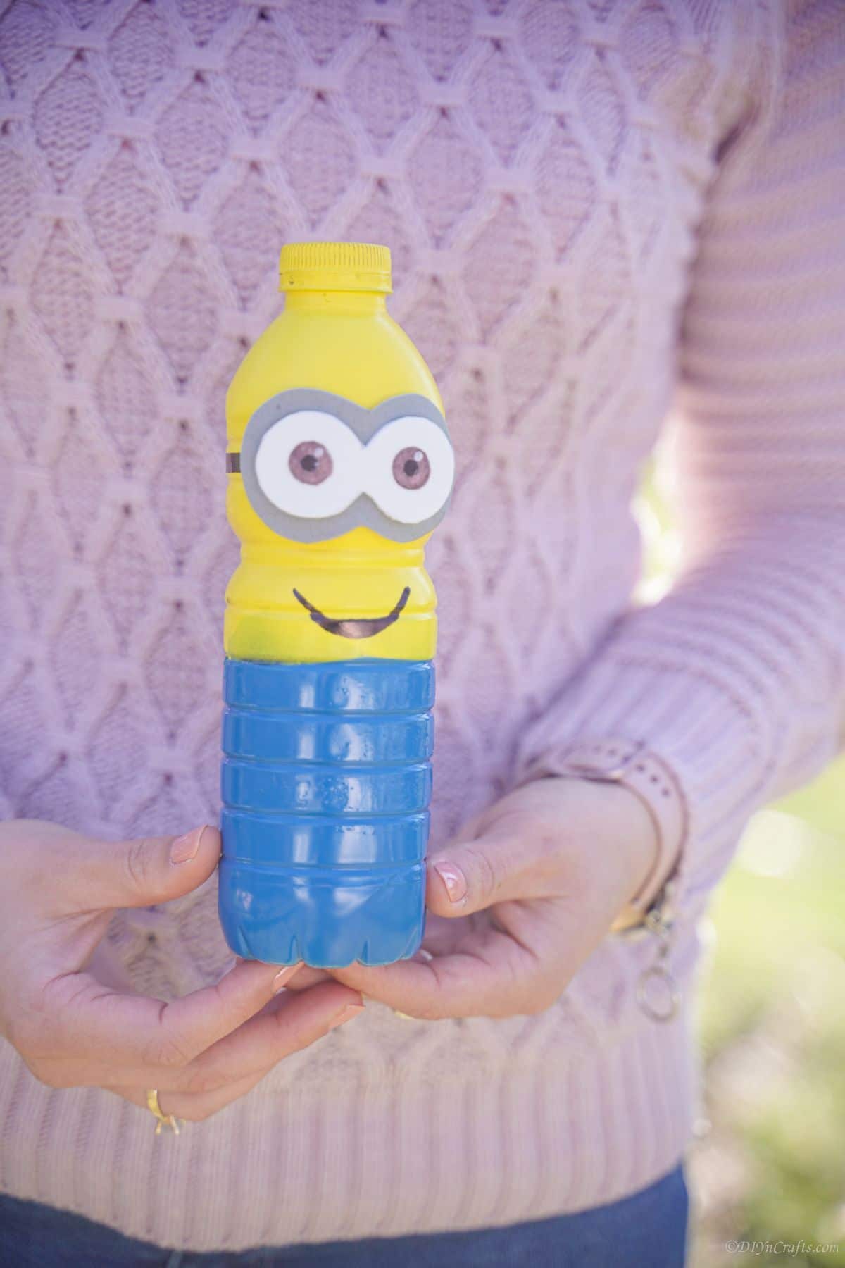 lady in pink sweater holding plastic bottle minion