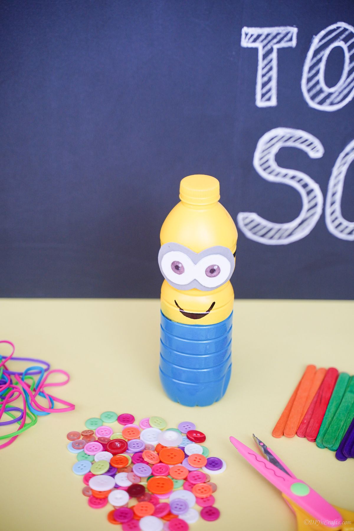 plastic bottle minion on table with chalkboard in background