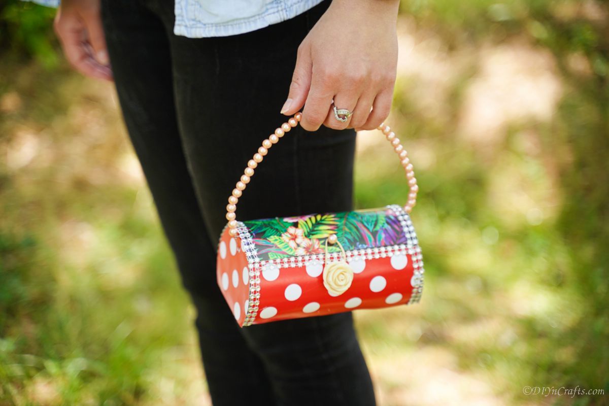 woman in black pants holding plastic bottle purse with red polka dots