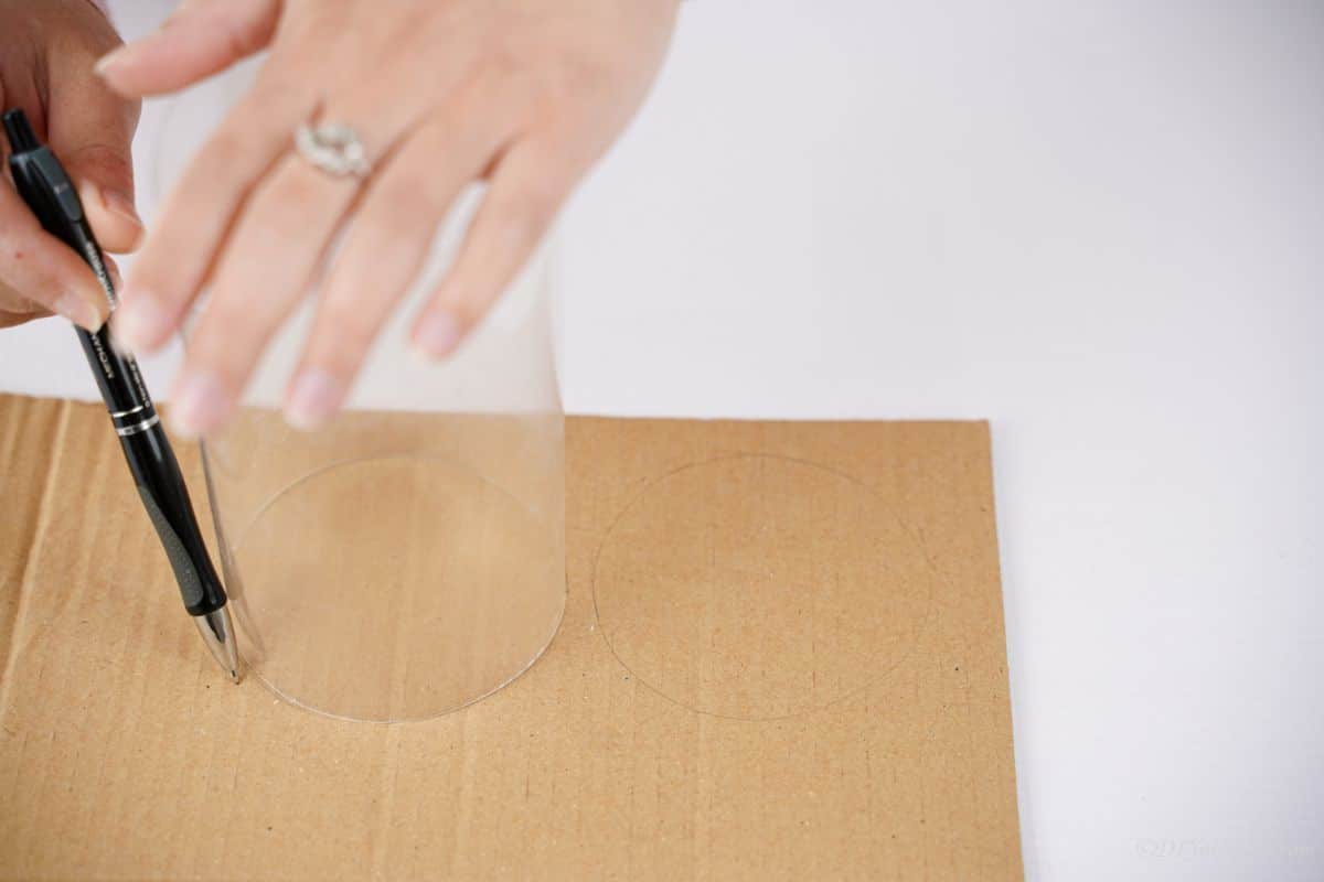 hand holding plastic to trace onto cardboard