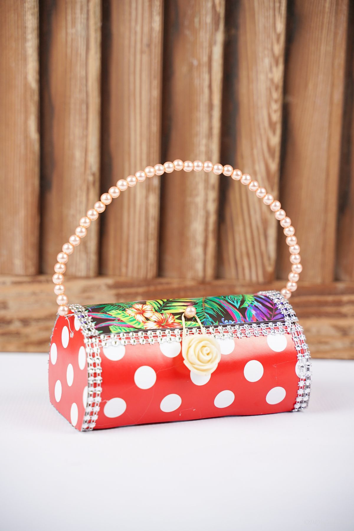 wood paneling behind small red and white purse with colorful flower top