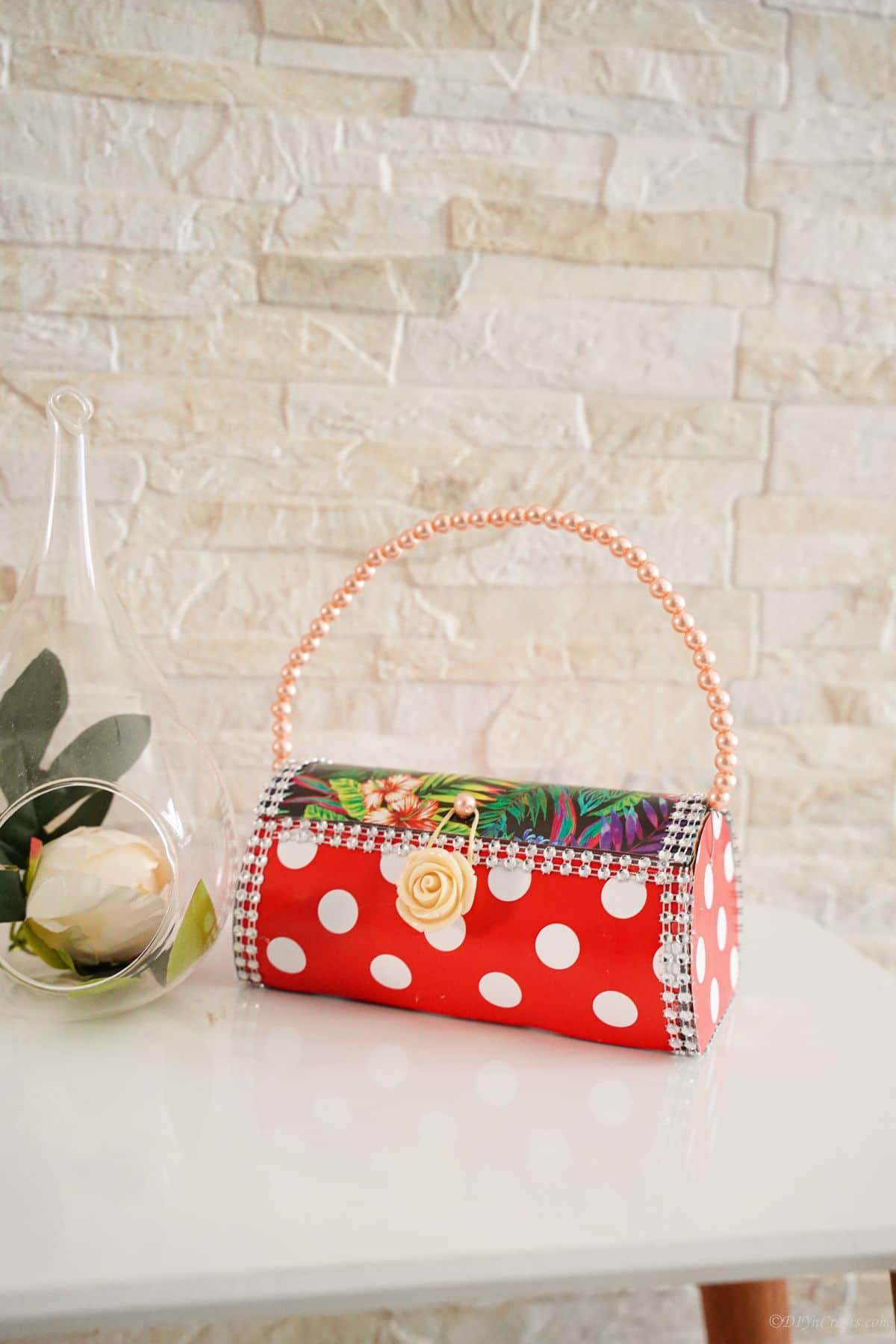red and white purse on table with cream brick background