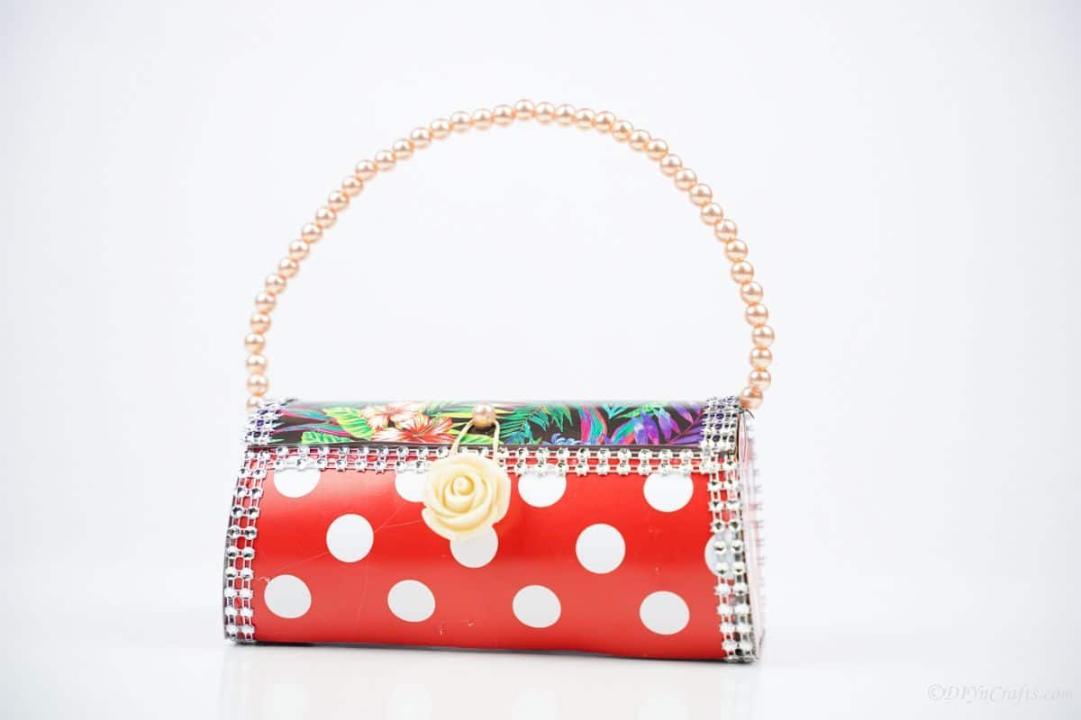 white background behind colorful small handbag with pearl handle