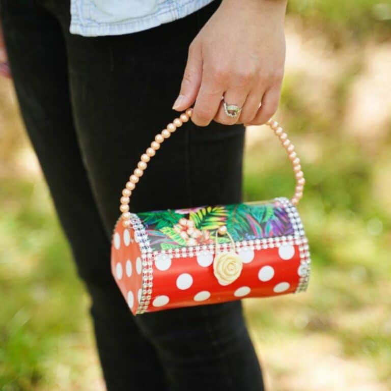 woman in black pants holding plastic bottle purse with red polka dots