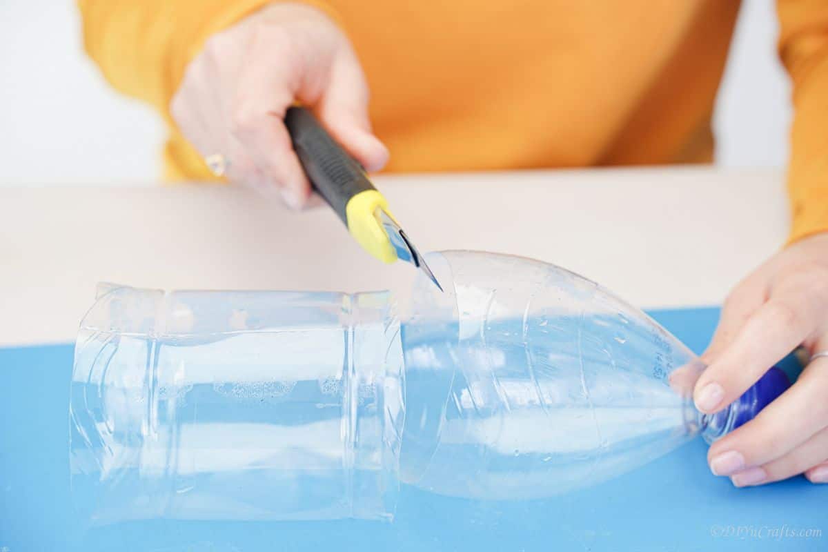 yellow craft knife cutting bottle on blue mat